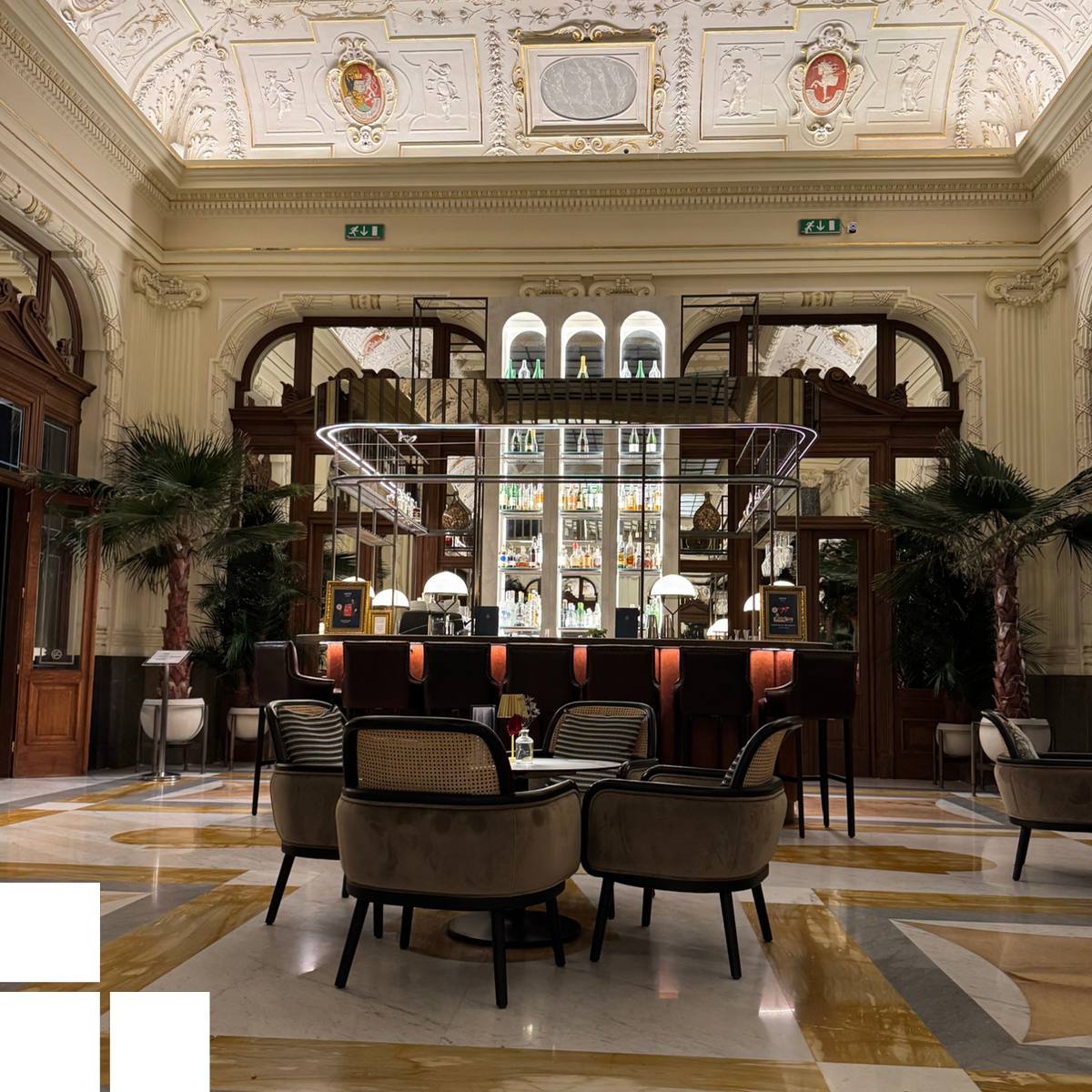 Blick in die Lobby eines altehrwürdigen Hotels mit eleganten Sitzmöbeln im Vordergrund.