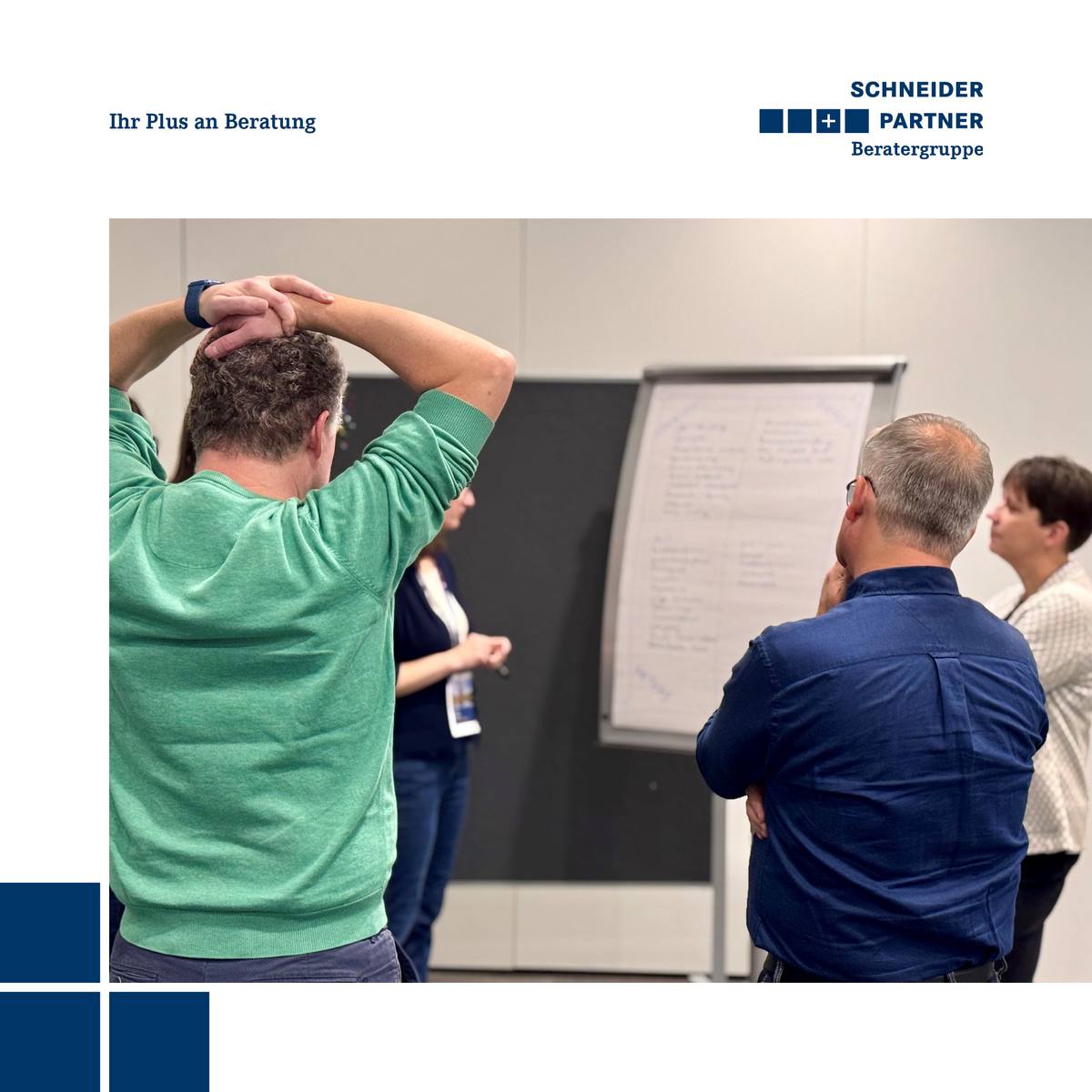 Zwei Männer und zwei Frauen schauen in einer Workshopsituation konzentriert auf ein Flipchart.
